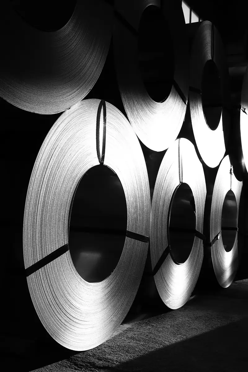 Rows of strapped metal coils standing in a warehouse, in black and white